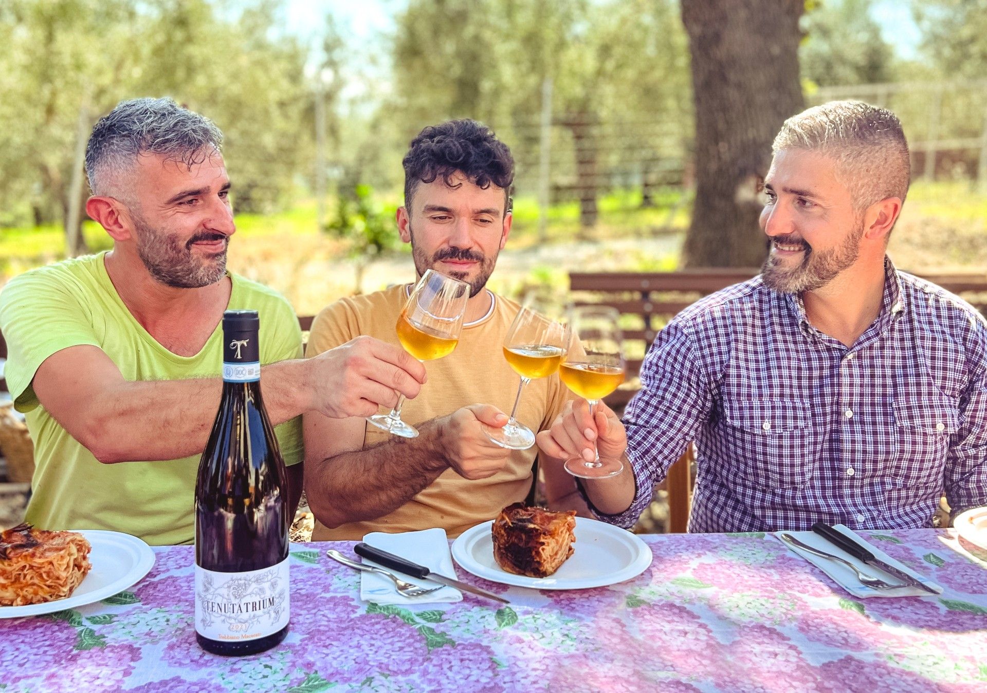 ragazzi che brindano durante il pranzo con calici di Trebbiano D'Abruzzo macerato della Tenuta Trium di Notaresco a Teramo