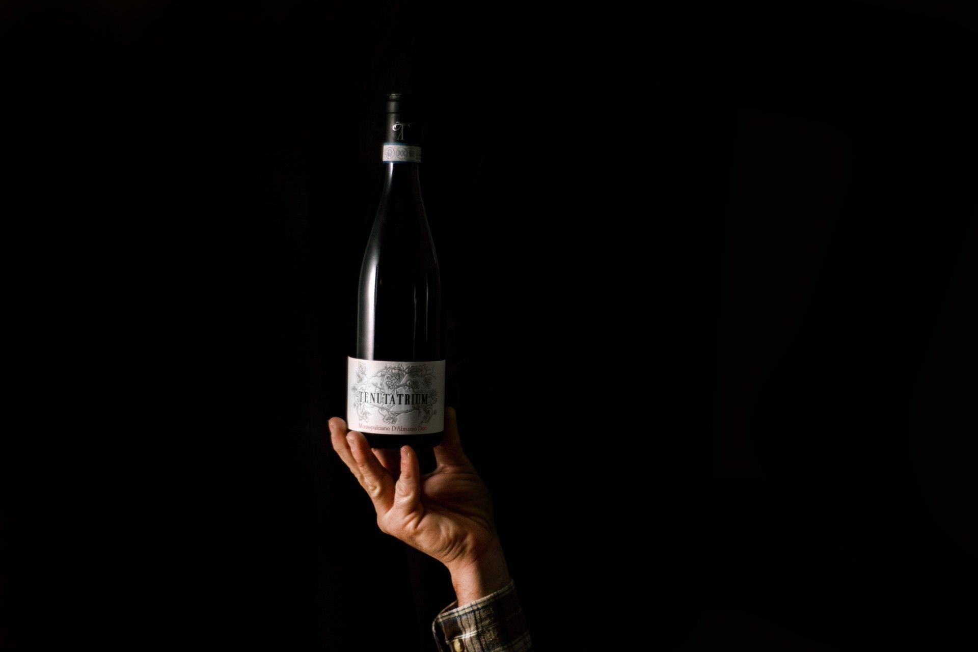 bottiglia in mano di Montepulciano D'Abruzzo DOC della Tenuta Trium di Notaresco a Teramo in Abruzzo