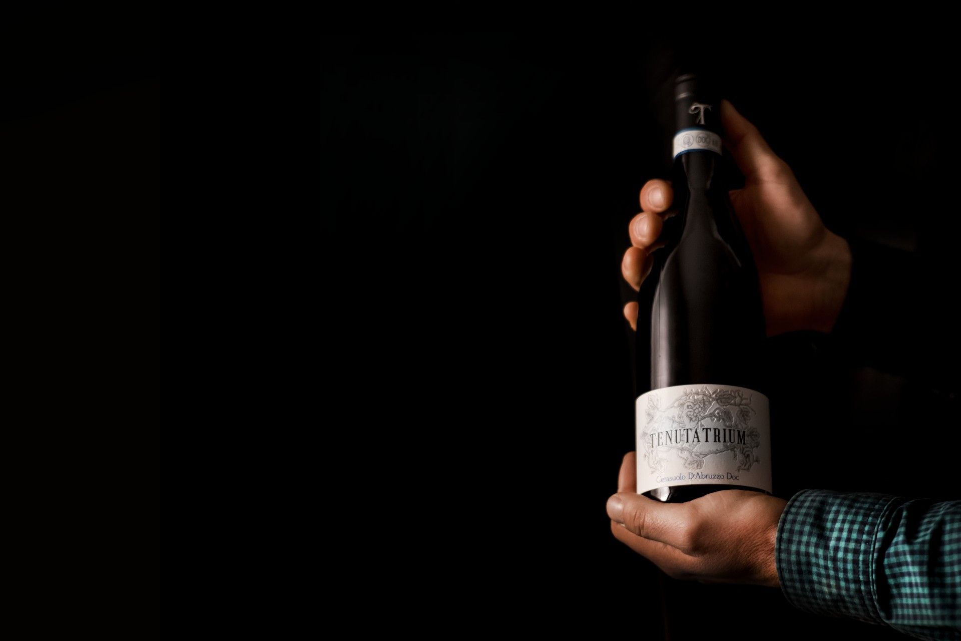 bottiglia in mano di Cerasuolo D'Abruzzo DOC della Tenuta Trium di Notaresco a Teramo in Abruzzo